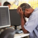 Mand tager sig til hovedet foran en computer