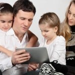 Ung familie med to børn ser på en iPad tablet