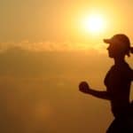 kvinde løber med solopgangen som baggrund